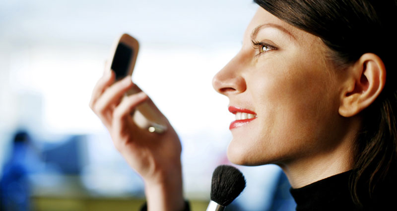 Businesswoman applying makeup